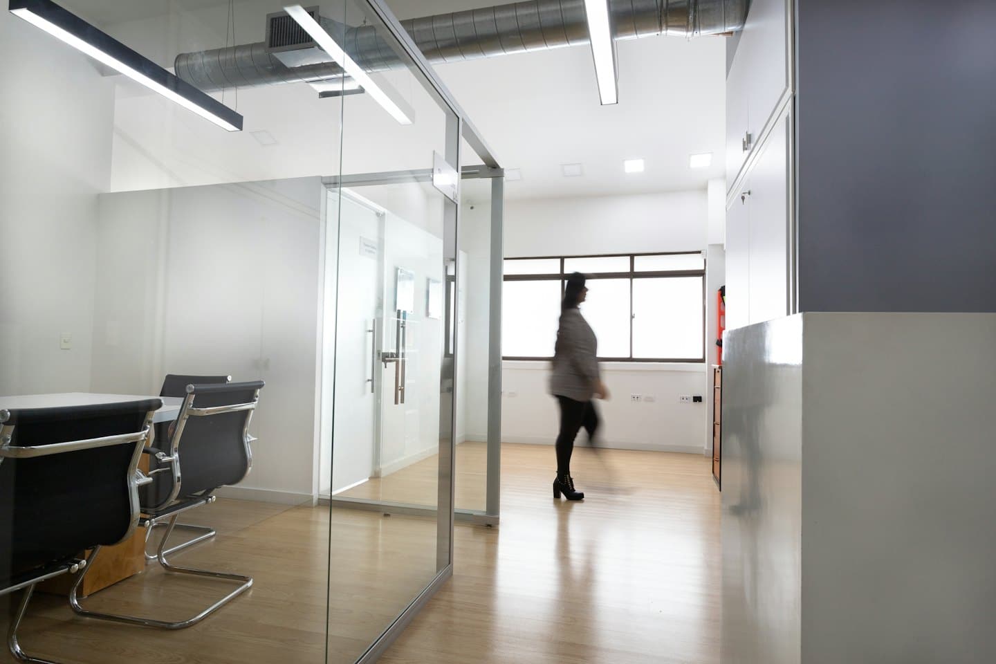 A person walks through a bright modern office hallway.